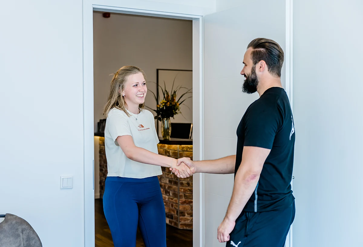 Der Physiotherapeut Marcel Ressin, von ALC-Physiolab aus Köln, begrüßt eine junge Patientin per Handschlag.